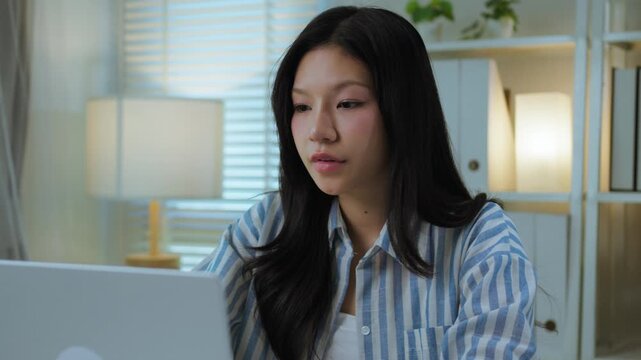 Asian Woman Sitting at Desk with Hand on Cheek Looking Tired and Bored. Work Fatigue and Burnout Professional Lifestyle Moment.