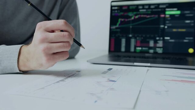 Professional financial trader analyzing stock market technical analysis charts on a laptop screen while working in a modern office environment