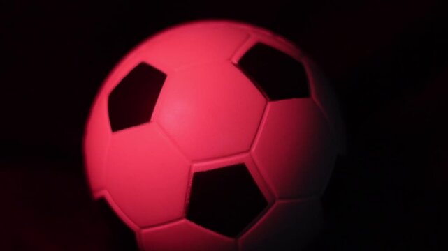 Una toma de cerca de una pelota o bal&oacute;n de f&uacute;tbol blanca con varias luces en un fondo negro