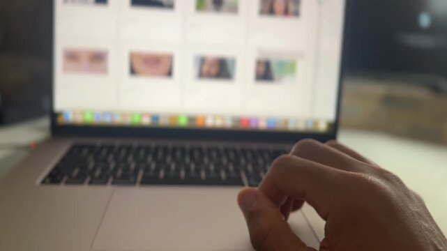 Hand of a man viewing a website on a laptop and browsing thumbnails