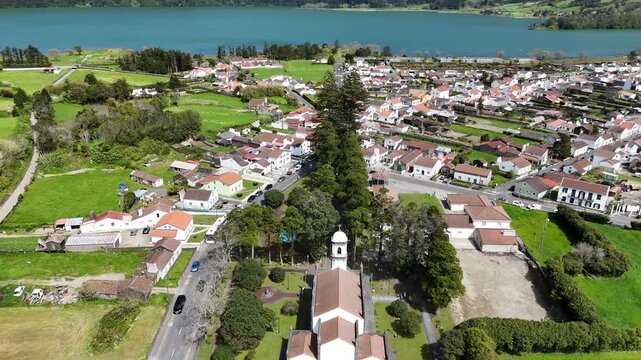 Aerial drone view of the traditional white houses and main church cathedral in Sete Cidades village. Scenic volcanic valley landscape on Sao Miguel Island, Azores, Portugal