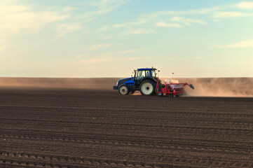 Naklejka premium Tractor working on agricultural field in spring