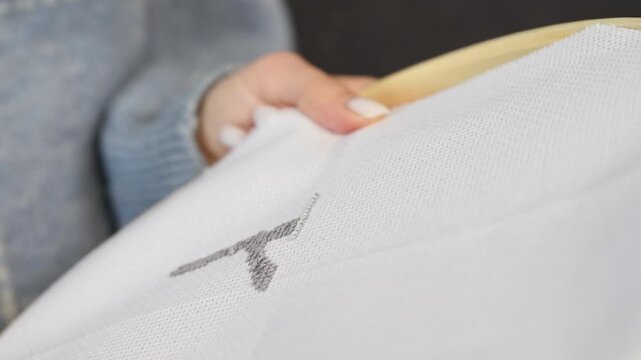 Hand embroidering black thread cross stitch on white fabric in neutral toned setting