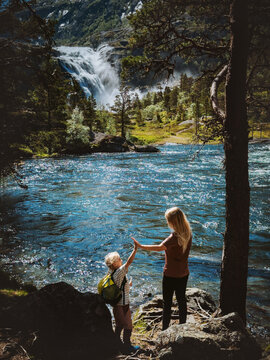 Family mother and kid hiking in Norway together, mom and child on camping trip in Husedalen valley outdoors active summer vacations parent and kid enjoying waterfall view bonding candid moments