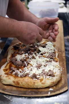 experto en pizzas echando ingredientes con su ano en una pizza artesanal