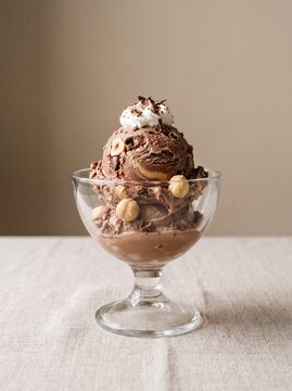 A professional photography shot of a single scoop of Bacio gelato in a glass cup, elegant studio presentation, neutral background.