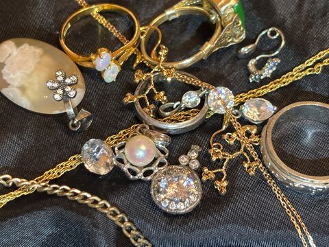 A rich collection of gold and silver jewelry with various gems on a black background.