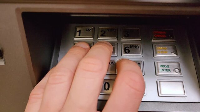 Close-up of a human hand entering a secret personal identification number on the keypad of an automated teller machine to withdraw money or access a bank account, ensuring privacy and security