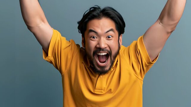 A jubilant man with dark hair, wearing a mustard yellow polo shirt, with his mouth wide open in a cheer.