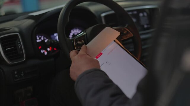 His hand is carefully touching the screen to navigate through the car scanning software and check for errors.The male technician is scanning the vehicle.He holds a digital diagnostic device.