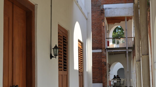 The front wall of the house features a brown wooden door and window, and is adorned with an antique lamp.