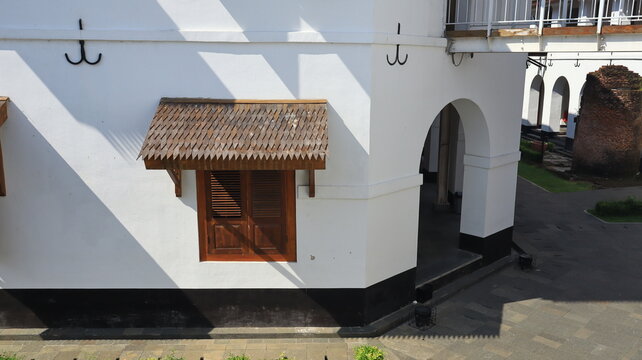A window on an old building is sheltered by a wooden roof.