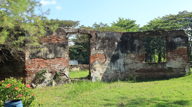 A wall made of red brick with a damaged coating is located at Van den Bosch Fort, Ngawi, East Java, Indonesia.