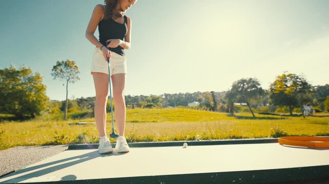 Young woman practices golf swing at sunny outdoor driving range in the afternoon