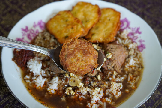 Traditional rawon Madura with beef, dark broth, steamed rice, bean sprouts, sambal, and fried side dishes in a close-up Indonesian culinary presentation.