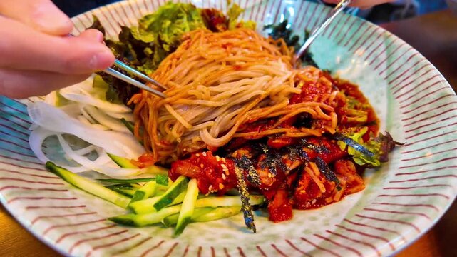 Makguksu stir with chopsticks, a traditional and popular noodle dish enjoyed especially in summer in Korea