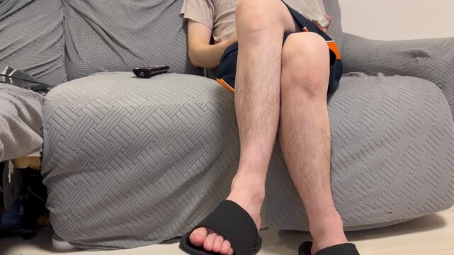 お菓子をソファーで食べる男性