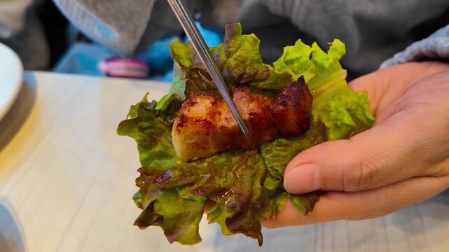 Ssam is a Korean food that wraps meat, kimchi, garlic and ssamjang on lettuce.