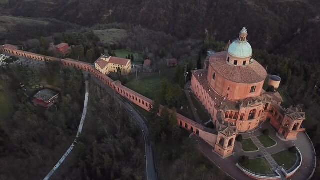 Aerial view of Santuario Madonna di San Luca and its long portico winding through the hills at sunset in Bologna, Emilia-Romagna, Italy.