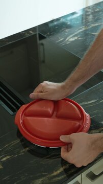Close-up shot of a meal being packed into a divided food storage container with pasta and patties, showing home cooking, leftovers, lunch preparation, takeaway food, portion control