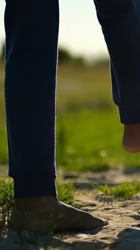 Vertical video: Lifting right foot, barefoot person in joggers controlling soccer ball on sand