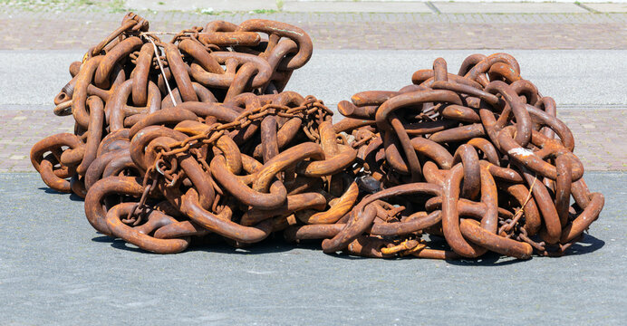 Rusty anchor chains lie outside on the street
