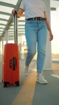 Woman confidently pulling a suitcase in an airport terminal. Slow motion.
