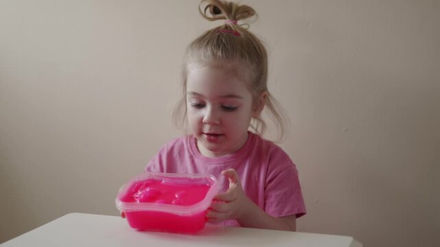 Child plays with pink slime at home and enjoys the texture and squishy feeling