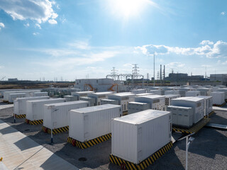 Fototapeta na wymiar White containerized energy storage systems arranged in an outdoor power station facility