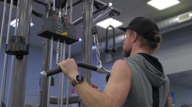 Man works out at gym using pulldown machine while focusing on fitness and strength training