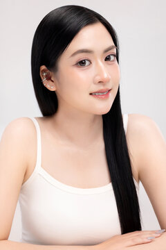 Portrait of beautiful Asian young woman with clean fresh glowing skin and long straight black hair, smiling, beauty and skincare concept, isolated on white background.