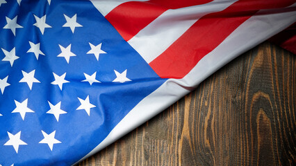 Obraz premium United States flag draped over a rustic dark wooden background with copy space. Ideal for patriotic holidays like Memorial Day, Veterans Day, and 4th of July