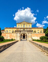 Fototapeta premium Grand Historic Palace Entrance Framed by Sunny Driveway Under Blue Sky