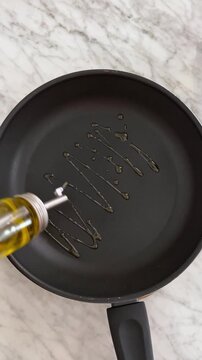 applying cooking oil to the surface of the frying pan to lubricate it, thus preventing food from sticking.