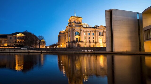 Hyperlapse of Reichstag parliament building in Berlin Germany. Spree river, reflections in the water, building illuminations on a clear evening 