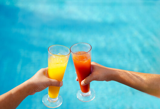 refreshment fruit juice water melon and pineapple in hands of couple swimming pool background, tropical beverage glass of fruit juice tomato and orange poolside resort hotel summer holiday vacation