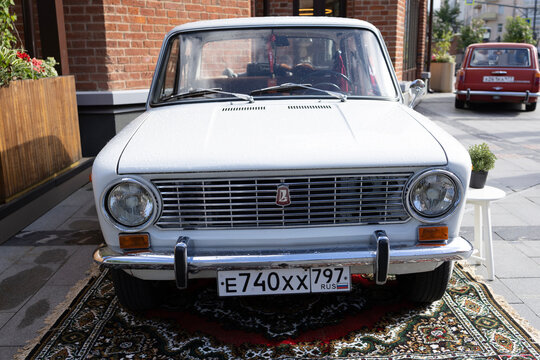 Classic soviet vintage cars lada vaz 2101 on city street exhibition near cafe under blue sky