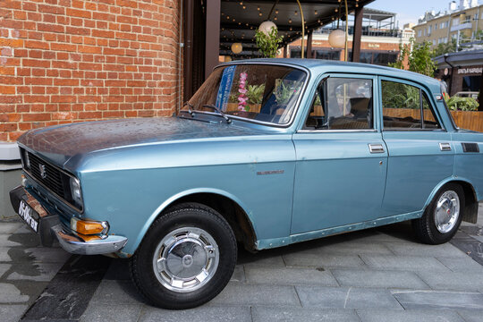 Classic soviet light blue sedan car moskvitch 2140 with chrome wheel cap at outdoor urban exhibition near brick wall