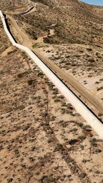 Aerial shot of the Los Angeles Aqueduct as it passes over some low mountains in California. The aqueduct supplies water to Los Angeles and Southern California. Vertical video.