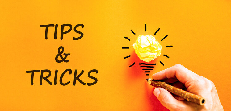 Tips and tricks words symbol. Concept words Tips and tricks on beautiful orange paper. Beautiful orange background. Businessman hand. Business tips and tricks motivational support concept. Copy space.