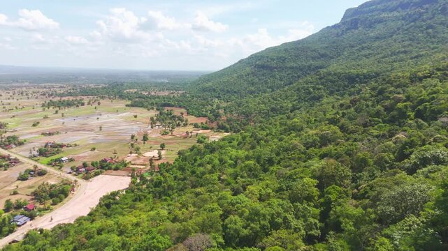 Aerial footage of the distinctive flat-top mesa formation near Khamtay Cave, Attapeu Province, southern Laos. The drone glides past the forested tabletop mountain revealing the wide agricultural valle