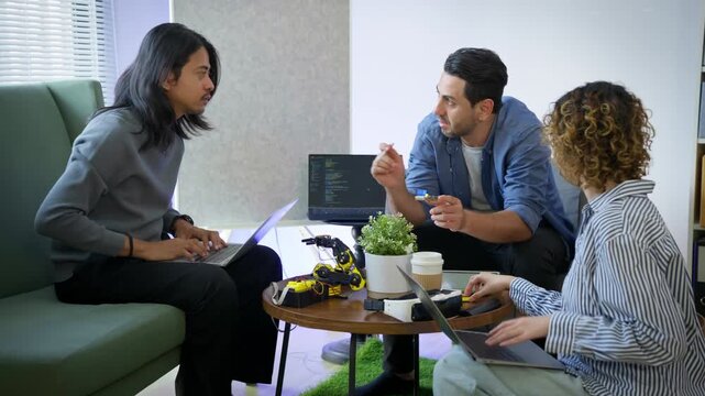 Diverse engineers and developers collaborating on robotics prototype project in modern startup lab. Robotic arm, VR headset, IoT development, embedded systems, hardware engineering, innovation team.