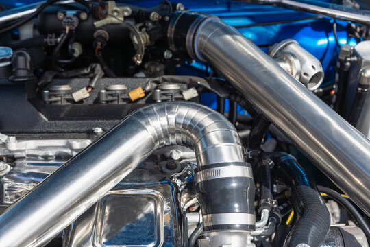 Close-up of turbo intercooler aluminum pipe and silicone hose in gas engine bay.