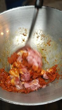 Close-up of stir-frying sliced pork with spicy red curry paste, crunchy yardlong beans, and herbal lime leaves in a wok. Food recipe process.