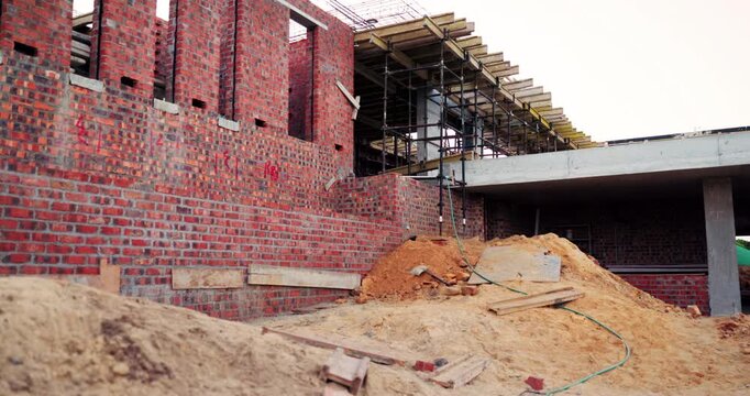 Construction, development and empty building at site, brick wall and concrete for engineering. Architecture, scaffolding and exterior with incomplete infrastructure, dirt and framework design