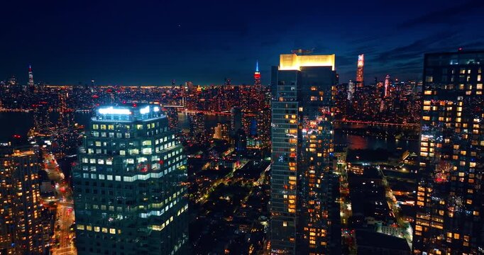 Moving away from the high-rises with neon light at the tops. Gorgeous New York City, USA at night. Drone footage.