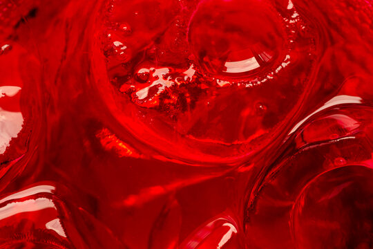 A very close-up image of an ice cube in a red liquid, a red macro drink,A vibrant and refreshing macro view of crystal clear ice cubes submerged in a brilliant red beverage, showcasing intricate.