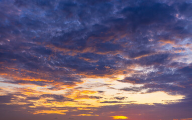 Fototapeta premium Dramatic Golden Hour Sky with Textured Clouds at Sunset,A breathtaking view of the evening sky filled with dramatic textured clouds illuminated by the golden rays of the setting sun, creating.