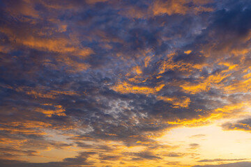 Fototapeta premium Dramatic Golden Hour Sky with Textured Clouds at Sunset,A breathtaking view of the evening sky filled with dramatic textured clouds illuminated by the golden rays of the setting sun, creating.