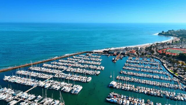 Footage over multiple rows of yachts and boas standing near the berths in the harbor. Marina of the Pacific Ocean near the shore of Santa Barbara County, California.
